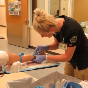 Nursing student drawing blood on in simulation.