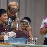 college students help young students with chemistry experiment