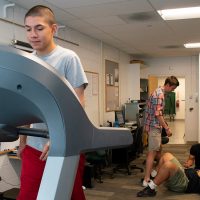 male student on treadmill students in background testing fitness