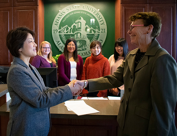 Chiho Sugo and Adams State President Cheryl D. Lovell shake hands