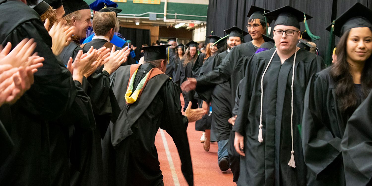 graduating students get high fives from professors after commencement