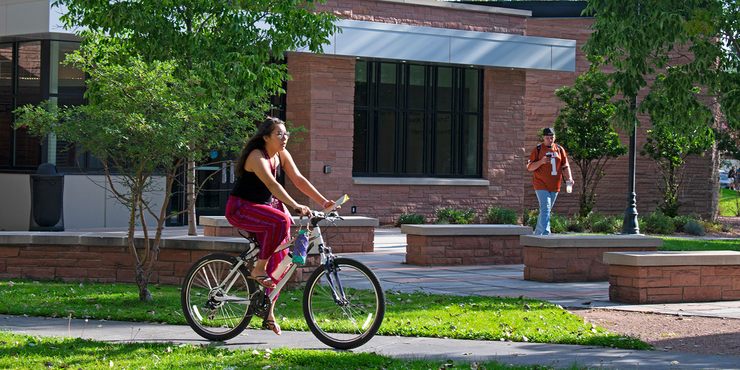 Adams State student riding bicycle