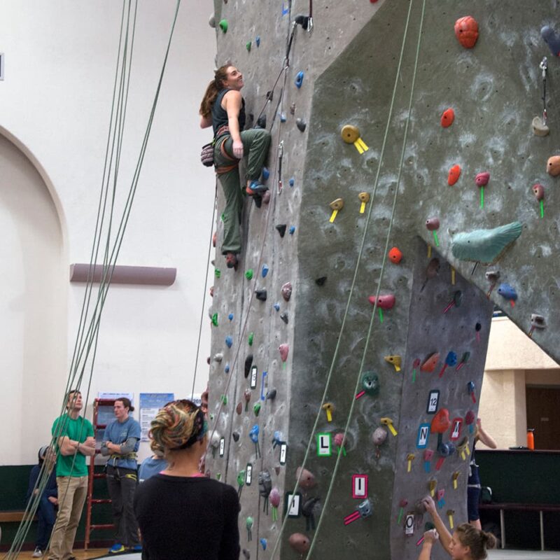 students watch a climber at the Rex Activity Center climbing wall