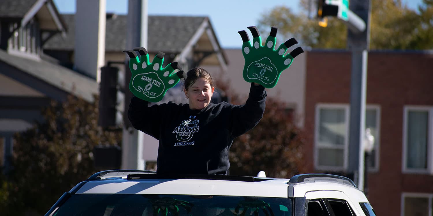 Adams State homecoming parade participant waves ultra large hands