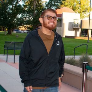 student on campus in front walking into Richardson Hall