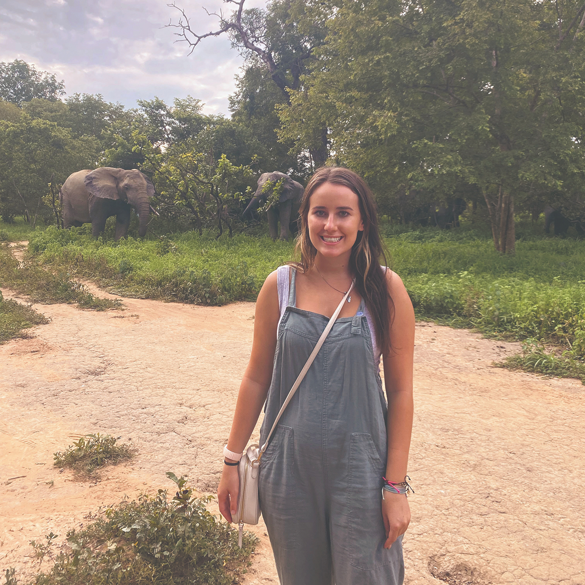 Ariel Caldon stands in front of elephants in the bush
