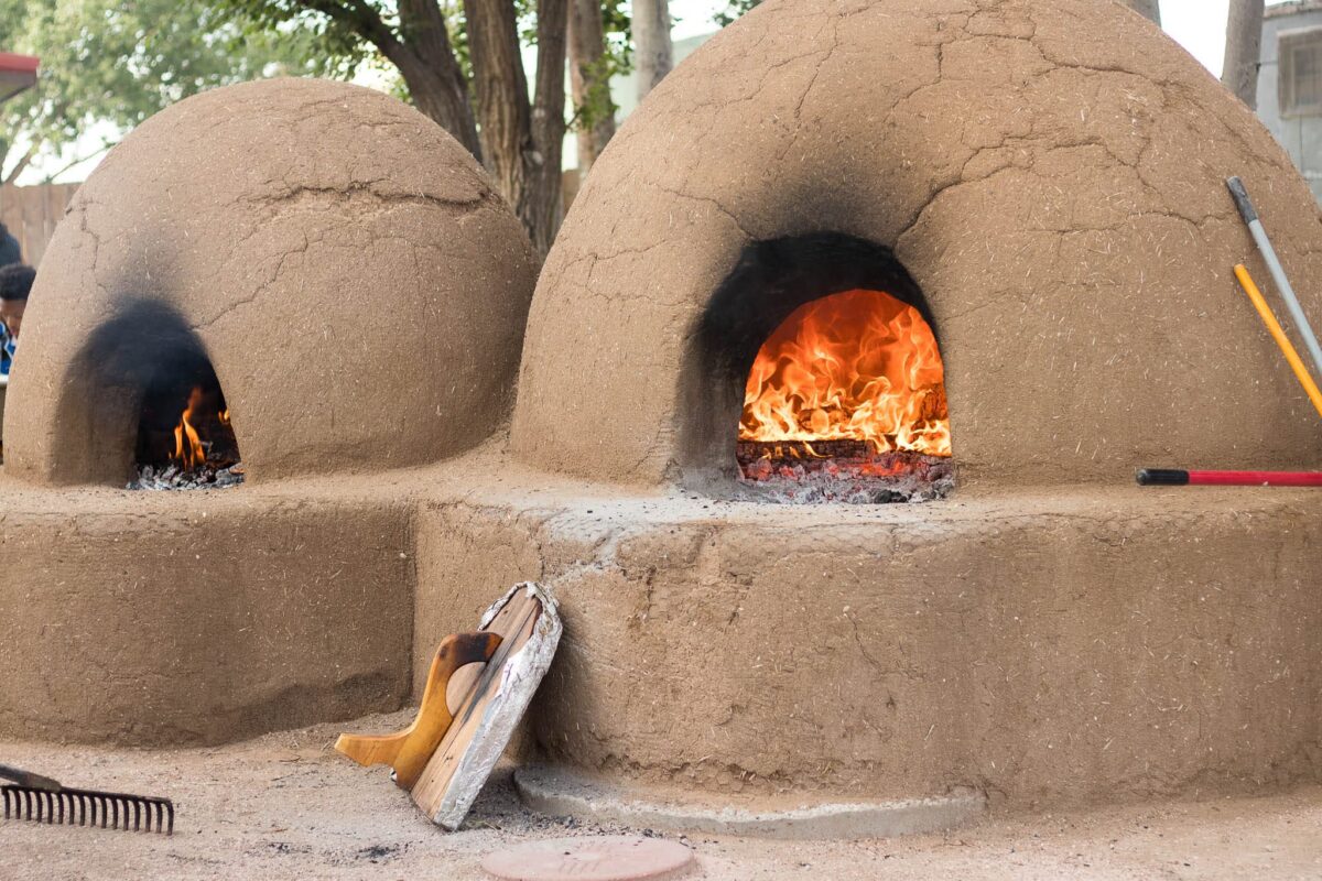 We see two traditional adobe hornos used for baking with fires inside.