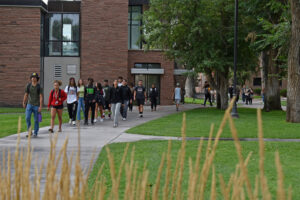 Students walk on Adams State's main sidewalk near the Music Building on the South Campus. 