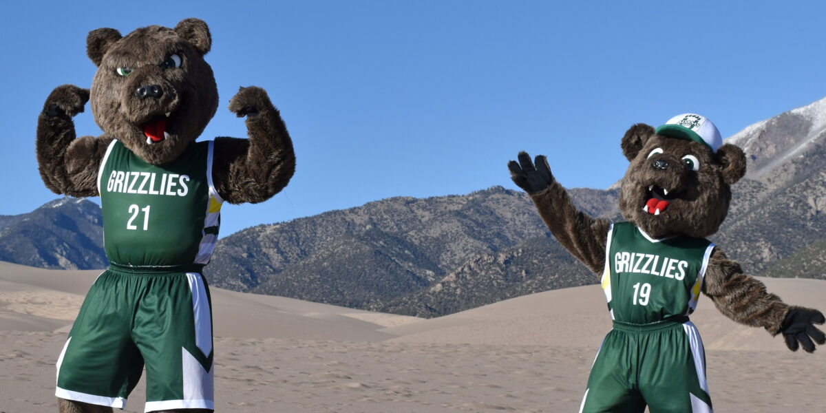 Adams State Grizzly mascots Russet and Billy gesture at the Great Sand Dunes.