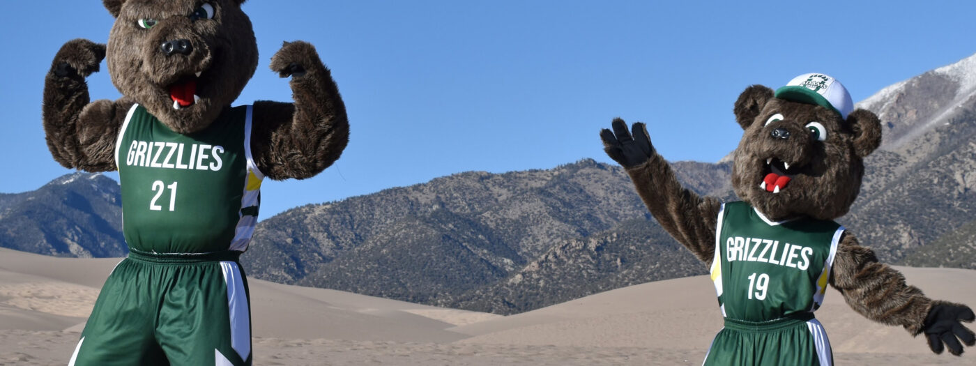 Adams State Grizzly mascots Russet and Billy gesture at the Great Sand Dunes.