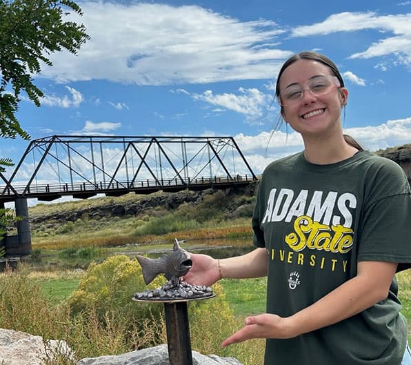 Adams State University sculpture student with bronze sculpture at Lobato Bridge