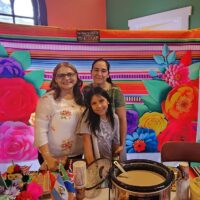 Elisamaria Heredia (left) serves a Mexican beverage called champurrado. She is assisted by Juana Hernandez Alcantar and her daughter, Katherine Arce Hernandez