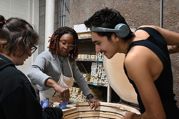 Annaliesa Connor-Meissner helps ceramic students load projects into kiln.