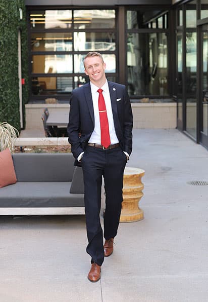 Adams State University 2026 Exceptional New Alumnus Kole Kelley in front of office building