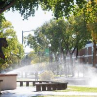 Adams State University Old Mose sculpture with sprinkler watering grass and trees