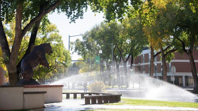 Adams State University Old Mose sculpture with sprinkler watering grass and trees