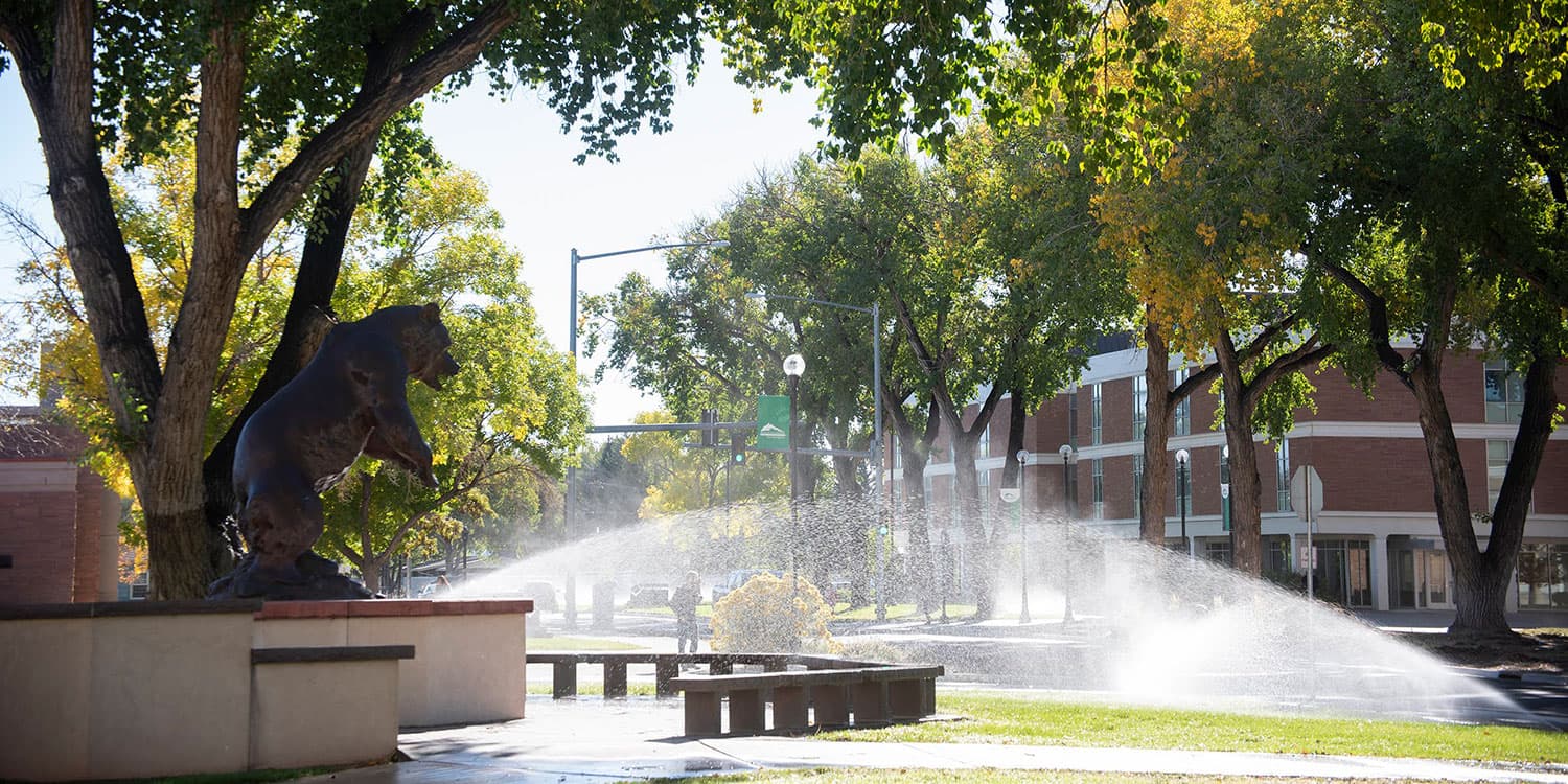 Adams State University Old Mose sculpture with sprinkler watering grass and trees
