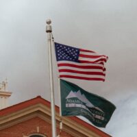 Adams State University Richardson Hall Cupola and US flag and Adams State flag flying in wind