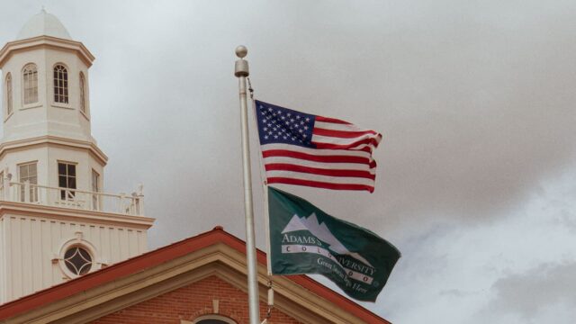 Adams State University Richardson Hall Cupola and US flag and Adams State flag flying in wind