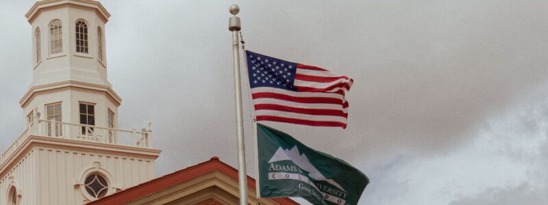 Adams State University Richardson Hall Cupola and US flag and Adams State flag flying in wind