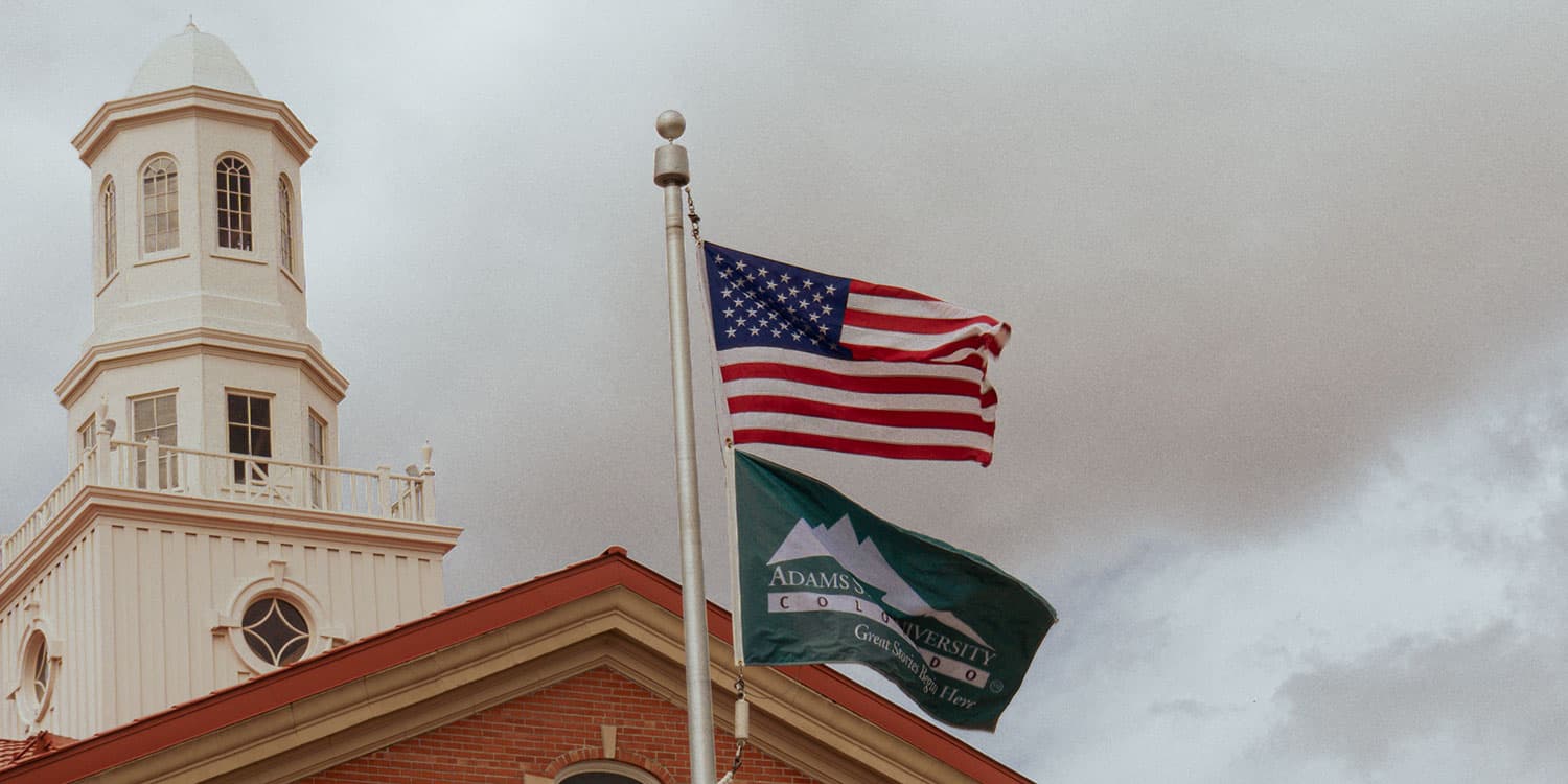 Adams State University Richardson Hall Cupola and US flag and Adams State flag flying in wind